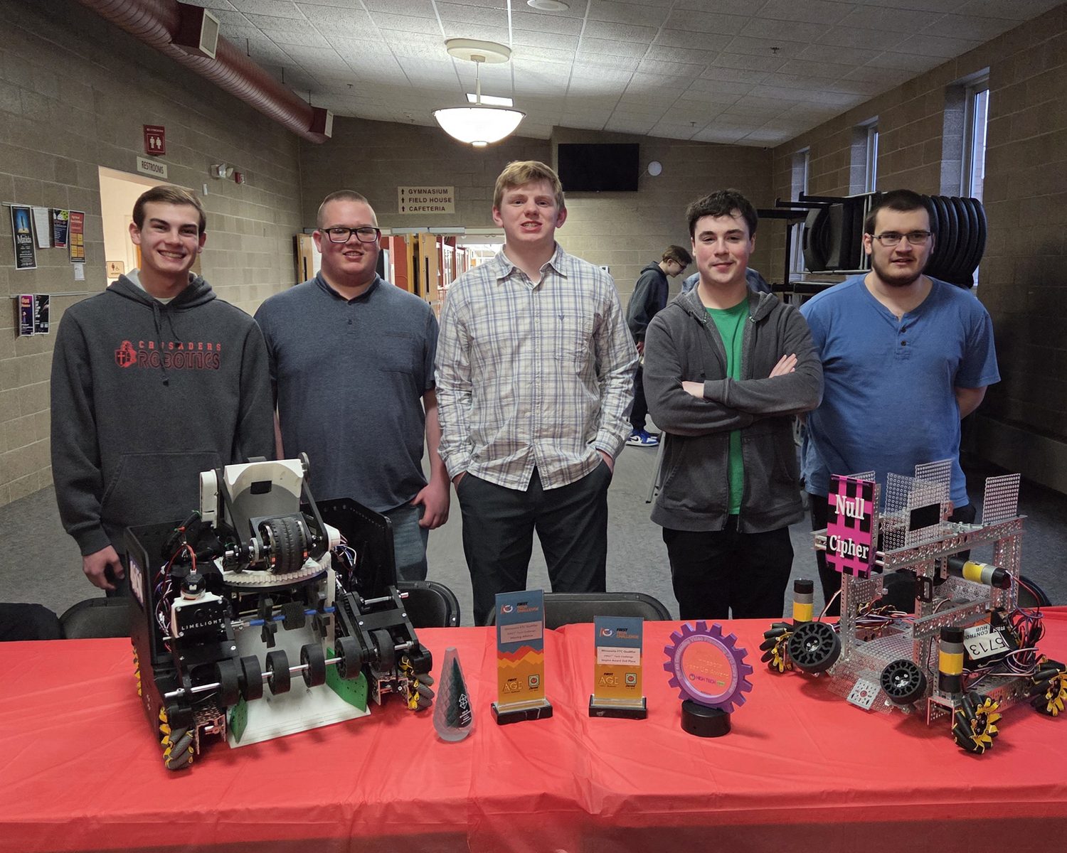 Students with two robots and trophies at the banquet